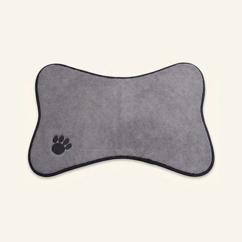 Light gray bone-shaped pet feeding mat with a black paw print logo in the corner