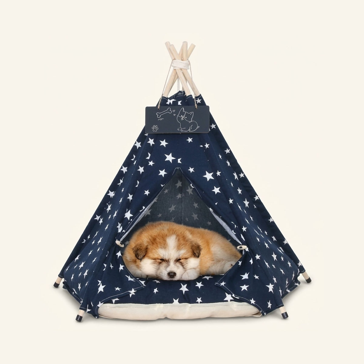 Navy blue dog teepee tent with white stars and a sleeping puppy inside on a cream cushion