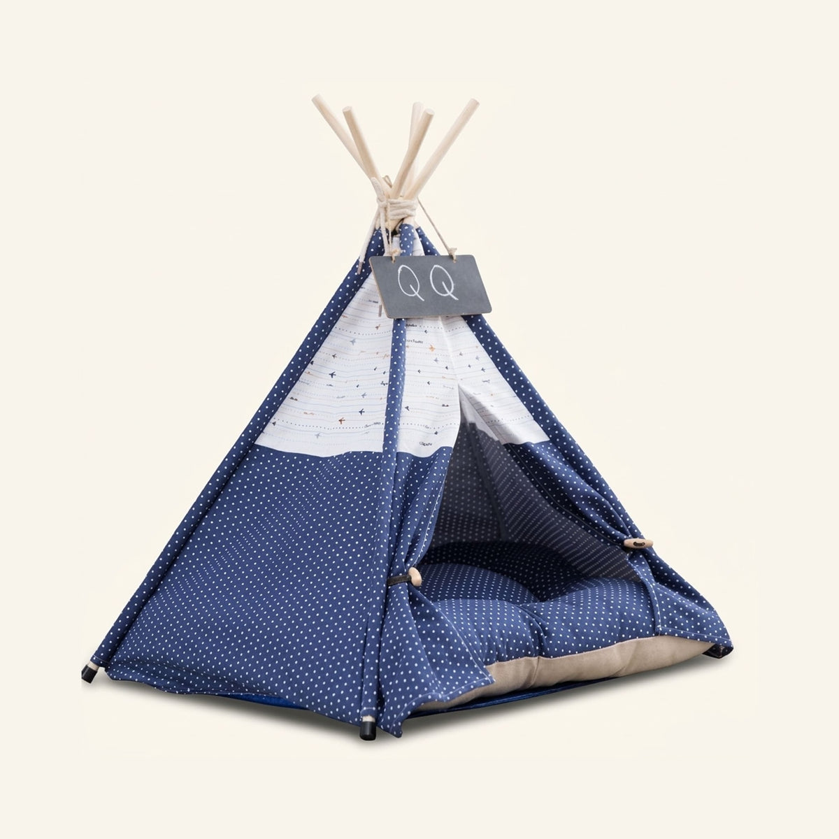 A navy blue canvas dog teepee tent with white polka dots and a matching cushion inside