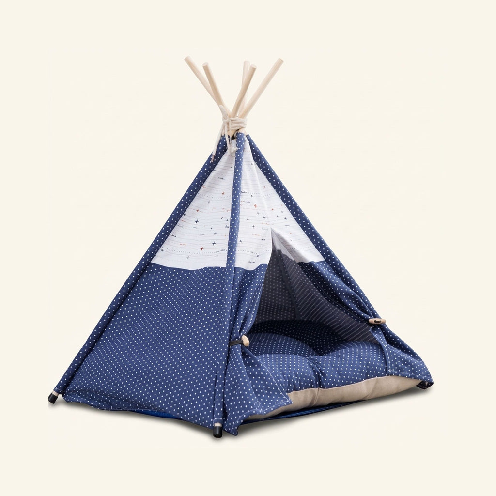 Blue polka dot canvas pet teepee tent with wooden poles and a matching cushion inside.